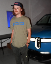 GRIDLIFE olive flag logo t shirt infront of Rivian R1S 