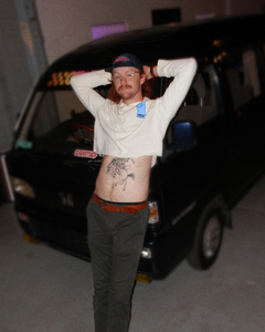 Model of the Women's peace cropped hoodie lounging on a Honda kei car