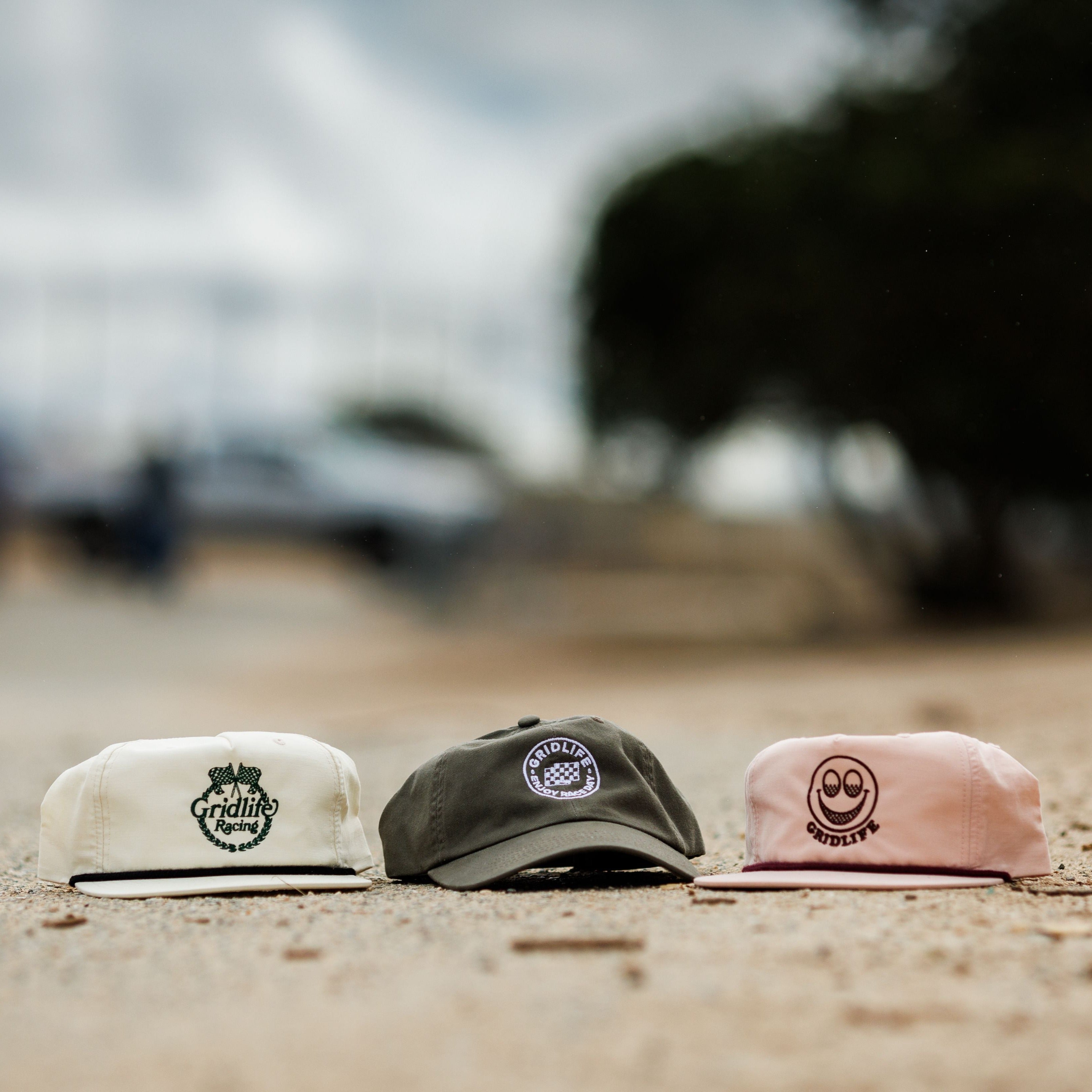 Assortment of GRIDLIFE hats. From left to right; Laguna Crest, Enjoy Raceday Dad hat, and the pink smiley